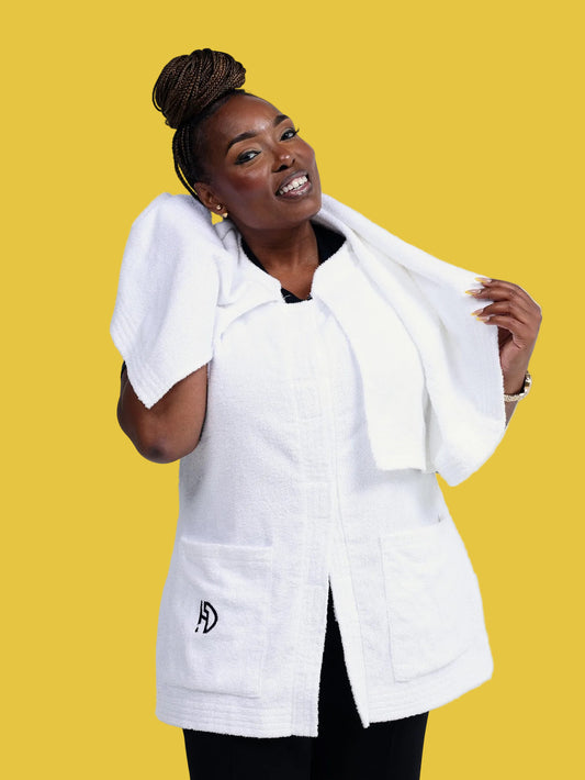 Woman wearing a white Hair Drip Wear premium microfiber towel garment with hood and front pockets, holding a matching white towel over her shoulders.